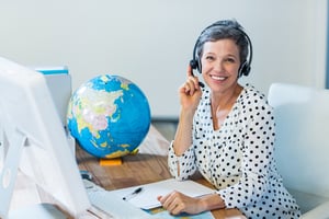 Tour, attractions and travel agent with a headset on by a computer desk. 