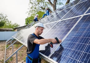 Solar installation technician installing solar panels on house