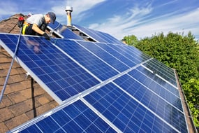 Technician installs solar panels on roof of home
